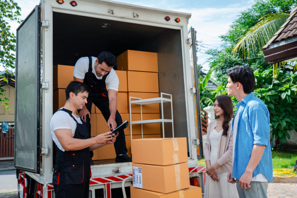 asian couple check while unloading boxes and furniture from a pickup truck to a new house with service cargo two men movers worker in uniform lifting boxes. concept of home moving and delivery.