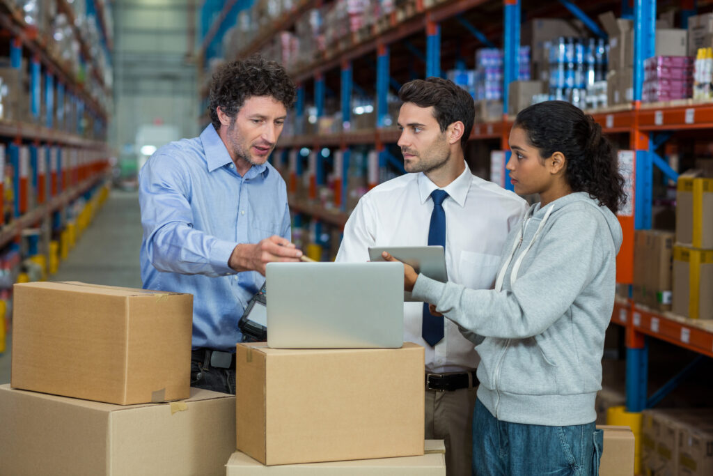 warehouse manager and worker discussing with laptop