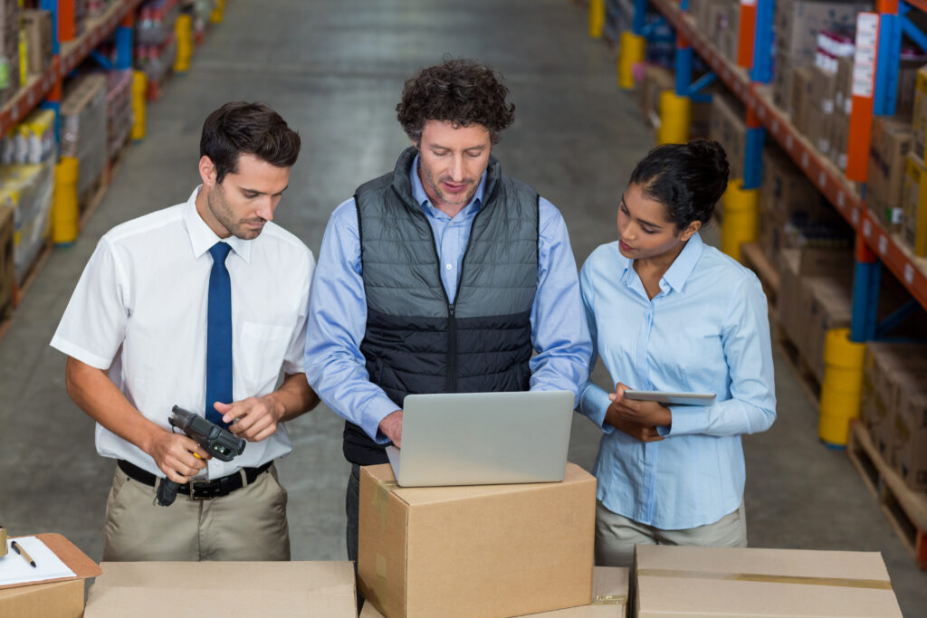 warehouse workers and manager discussing with laptop