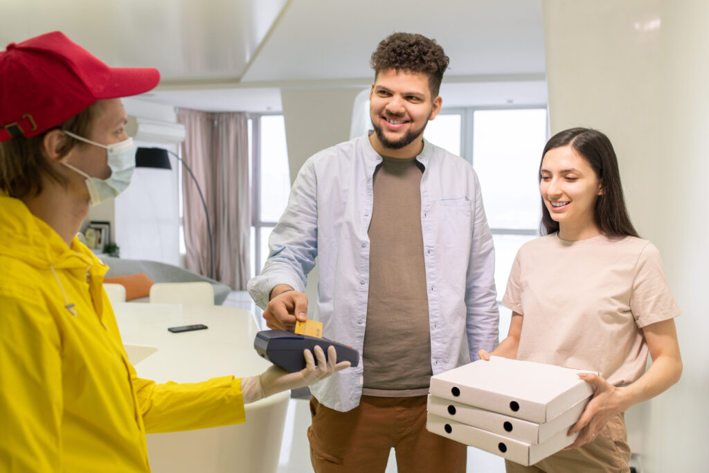 happy young man paying for pizza by credit card