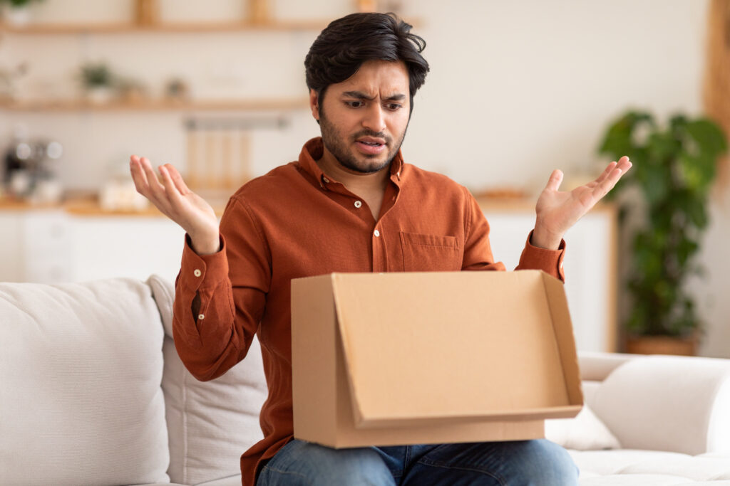 Why Bad Delivery Experiences Are Remembered disappointed man opening cardboard box in living room