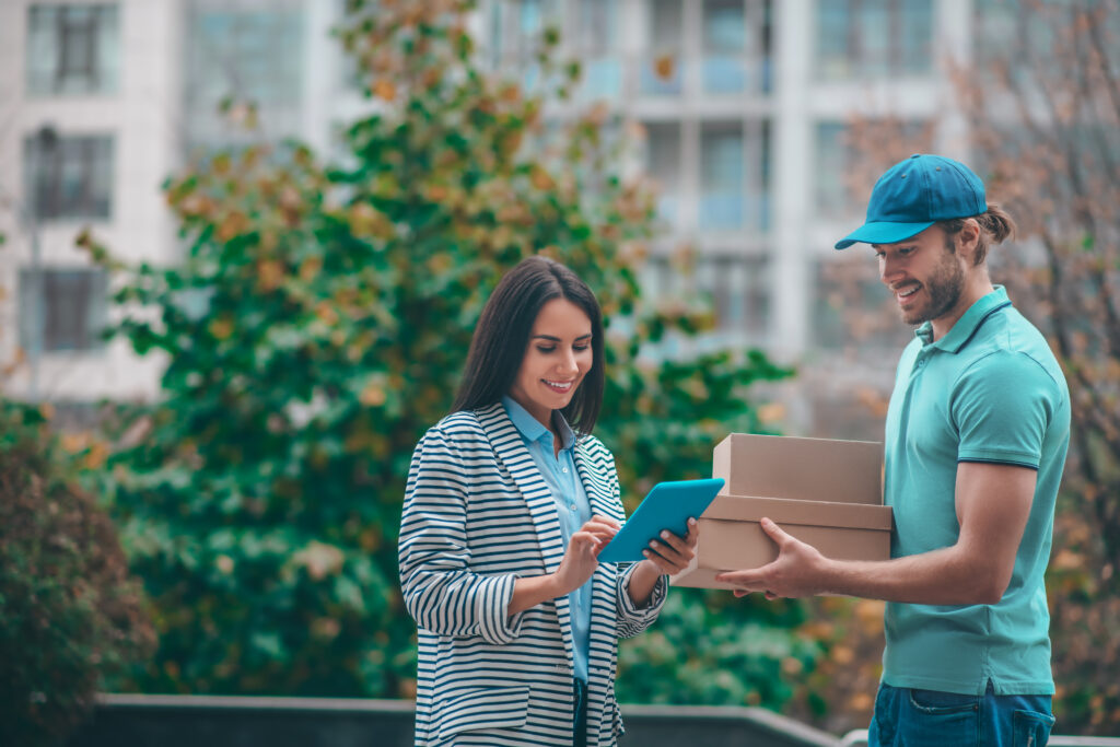 woman using tablet while standing near delivery man